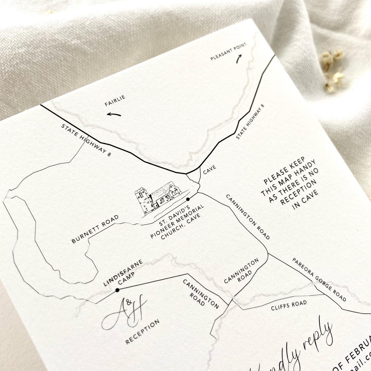 Hand-drawn map and couple logo on invitation on a textured card
