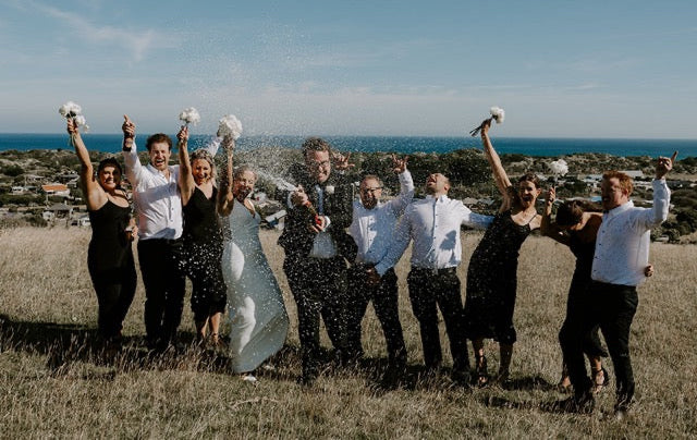 Group of people celebrating with champagne outdoors by the ocean at Lochend Woolshed