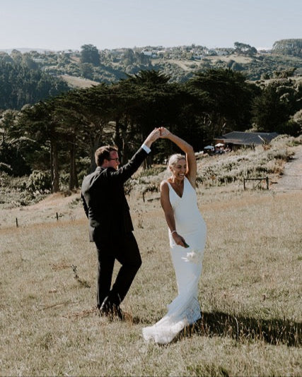 Man and woman dancing outdoors in a scenic landscape with trees and open space near Lochend Woolshed