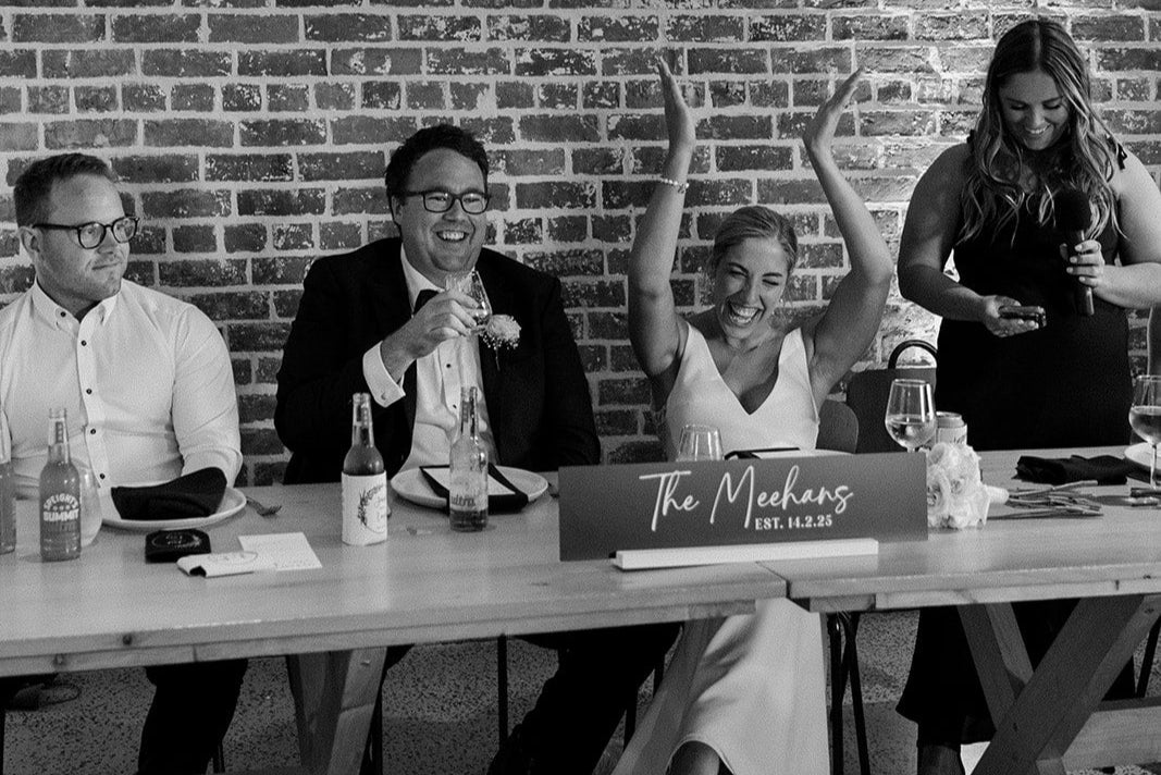 Group of people sitting at a table with a head table sign celebrating.