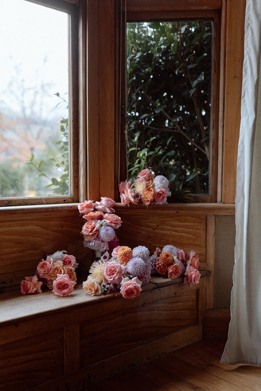 Floral arrangement on a windowsill with a view of trees outside