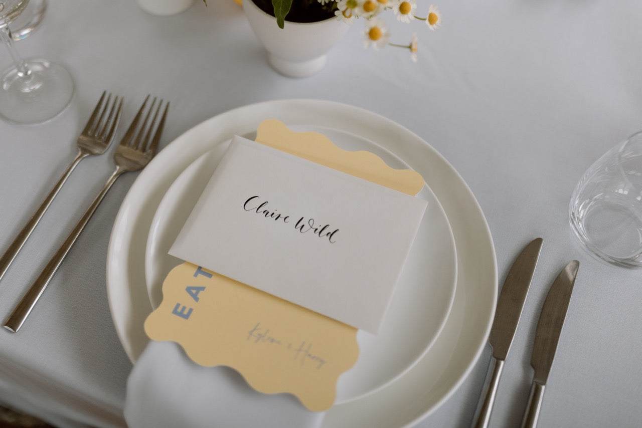 Table setting with white plates butter yellow menu, silverware on a white tablecloth at The Winehouse Queenstown