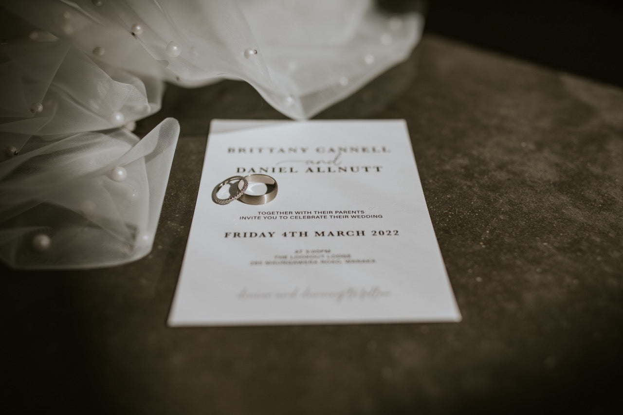 Wedding invitation card with floral decorations on a dark surface