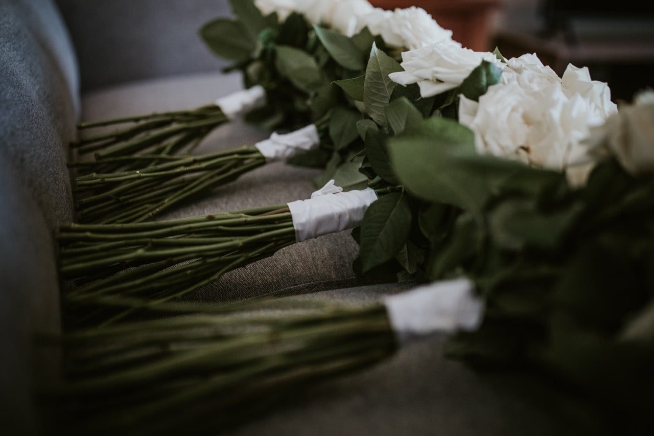 Bouquets of white roses with green stems on a textured surface