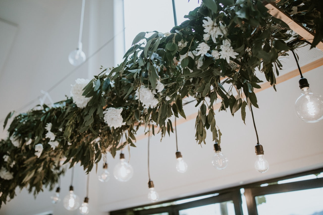 Decorative hanging plant with light bulbs against a neutral ceiling background