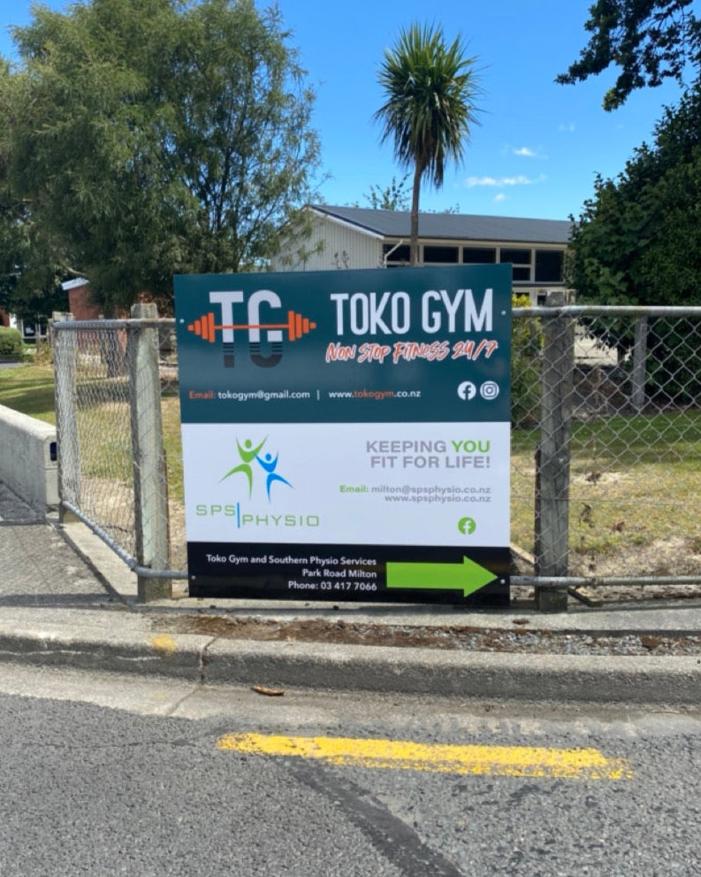 Toko Gym signage on a road with trees and a building in the background