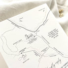 Hand-drawn map and couple logo on invitation on a textured card