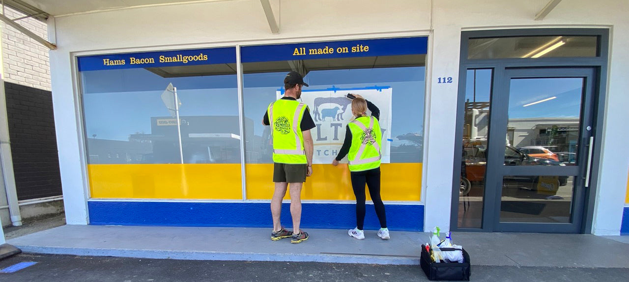 Remotelea Team in high-visibility vests standing applying window signage